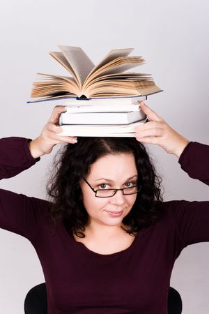 portrait of attractive woman with stack of books on her headの写真素材