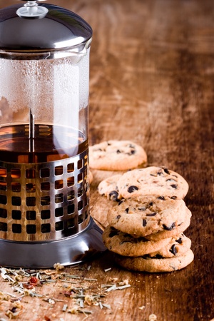 french press with hot tea and fresh baked cookies closeup on wooden tableの写真素材