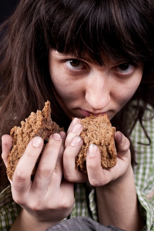 portrait of a poor beggar woman with a piece of bread in her handsの写真素材