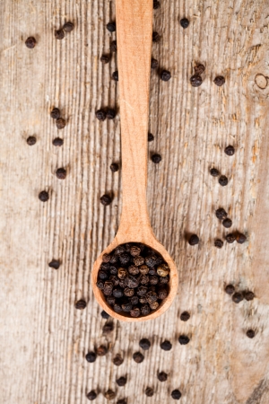 black pepper in wooden spoon on rustic wooden backgroundの写真素材
