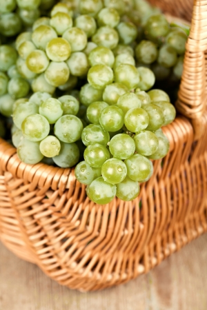 basket with fresh green grapes on rustic wooden tableの写真素材