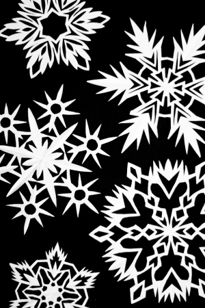 a lot of paper white cutout snowflakes on black backgroundの写真素材