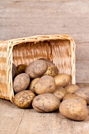 basket with fresh potatoes on rustic wooden background の写真素材