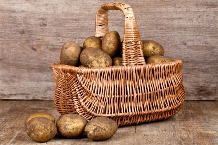 basket with fresh potatoes on rustic wooden background の写真素材