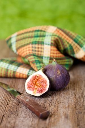  fresh figs, old knife and chequered towel on rustic wooden tableの写真素材