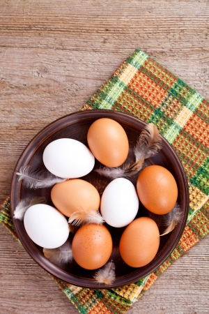 eggs in a plate, towel and feathers on rustic wooden tableの写真素材