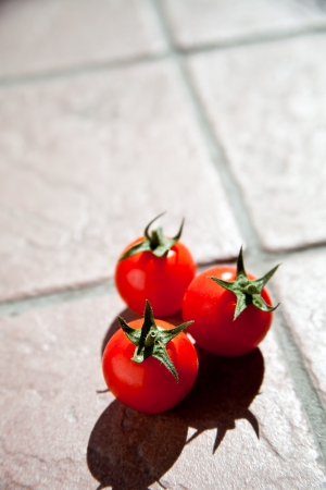 three cherry tomatoes on stone background の写真素材