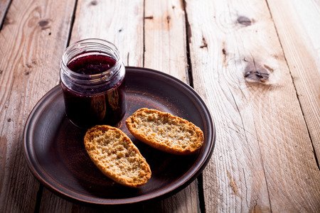 black currant jam in glass jar and crackers on rustic wooden boardの写真素材