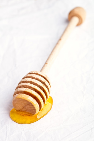 honey on wooden honey dipper on white background の写真素材