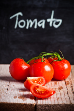 fresh tomatoes and blackboard on rustic wooden tableの写真素材