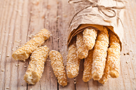 bread sticks grissini with sesame seeds in craft pack on rustic wooden background