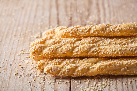 bread sticks grissini with sesame seeds on rustic wooden background