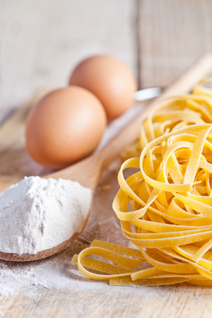italian pasta tagliatelli, flour and eggs close up on wood table の写真素材