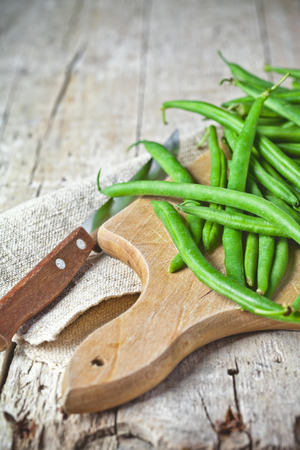 green string beans and knife closeup on wooden boardの写真素材