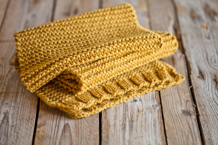 knitted yellow scarf on wooden backgroundの写真素材