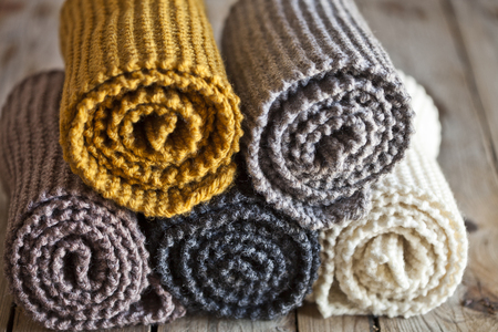 Five knitted wooden scarves yellow, brown, beige, grey, white closeup on wooden background