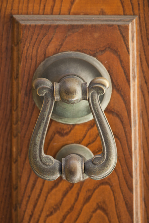 Ancient italian door knocker on brown door background.の写真素材