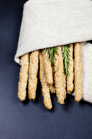 Italian grissini or salted bread sticks on linen napkin on black board background. Fresh italian snack. Top view.の写真素材