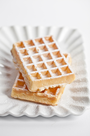 Belgium waffers with sugar powder on ceramic plate isolated on white background. Fresh baked wafers.の写真素材
