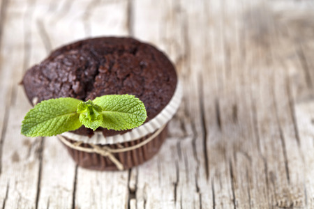 Chocolate dark muffins with mint leaves on rustic wooden table. With copy space.の写真素材