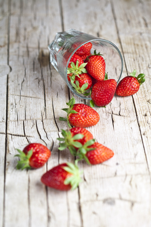 Organic red strawberries in glass on rustic wooden background. Healthy sweet food, vitamins and fruity concept.の写真素材