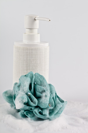 Liquid soap, green sponge and foam on light background. Closeup bathroom consept.の写真素材