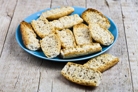 Fresh italian croutons crostini on blue plate on rustic wooden table background.の写真素材