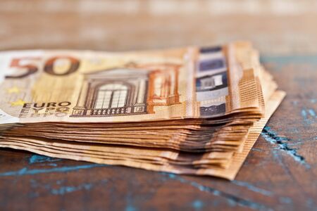 Pile of fifty euro banknotes. 50â¬ currency notes stacked on rustic wooden table background.の写真素材