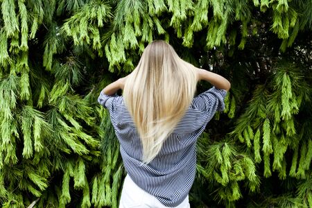 Beautiful young woman wearing elegant clothes standing in the forest against fir trees.の写真素材