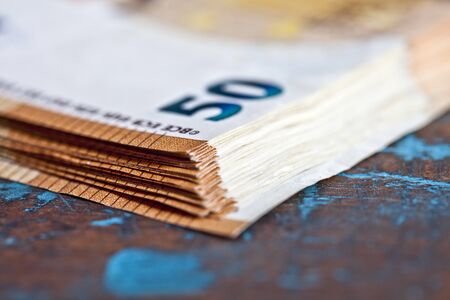Pile of fifty euro banknotes. Currency bank notes stacked on rustic wooden table background closeup.