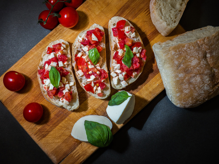Bruschetta on a wooden board, ingredients for bruschetta. Bruschetta with tomatoes, mozzarella and basilの写真素材