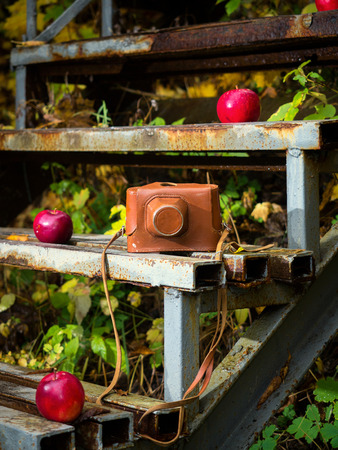 Old camera on a rusty ladder, camera and apples on the stairs, the camera on the background of the stairsの写真素材