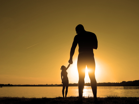 Silhouettes of a loving couple on the beach. Sunset on the beach. Giant and baby.の写真素材