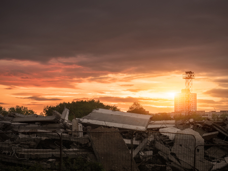 Destroyed building against the backdrop of the city and the sunset. Demolition of old buildings. Preparation for constructionの写真素材