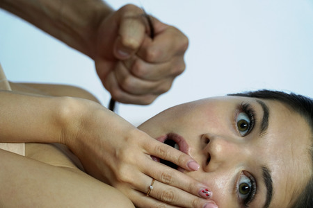 Portrait of a surprised girl. A man's fist squeezes a curl of female hair. Male power in sex. Back...