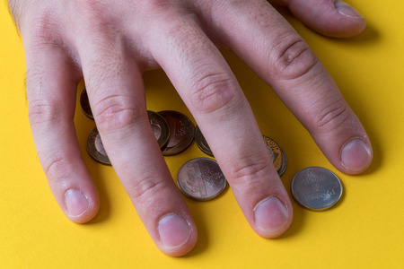 The man's hand covered the coins. Protecting your money. Lack of money.の写真素材