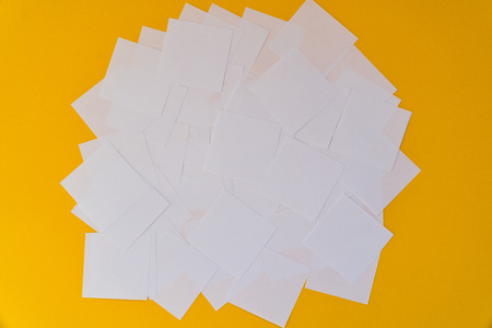 White square paper pieces spread out in chaotic order on a yellow background