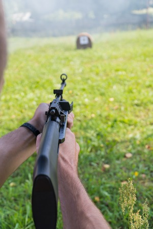 A man shoots a target from a pneumatic gun. A view from behind the shoulder.