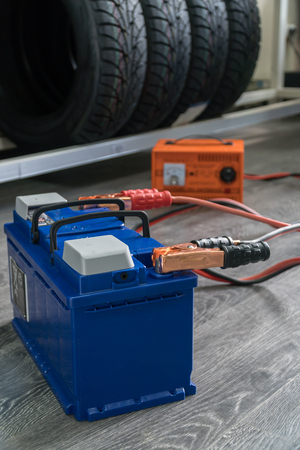 Recharging the car battery on a wooden background.の写真素材