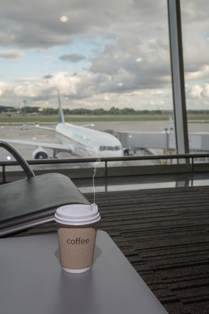 Cup of coffee in airport's business lounge with aircraft.の写真素材