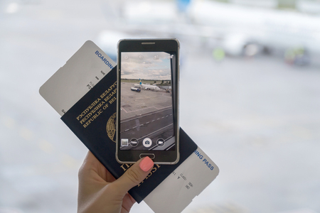Close up of woman hands taking photo of plane and hold passport with ticket. Travel Concept.の写真素材