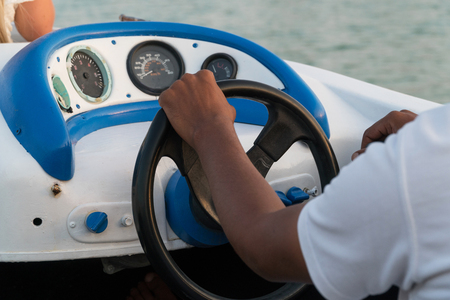 Men's hands on the steering wheel of a motor boat.の写真素材