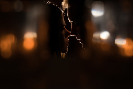 The guy tries to wake the girl with a kiss. Intimate evening.の写真素材