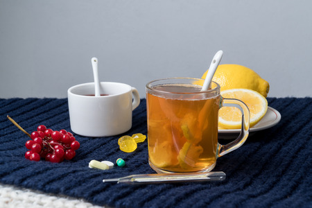 Still life of tea with lemon, tablets and thermometer, jam and berries. The concept of treating colds.の写真素材
