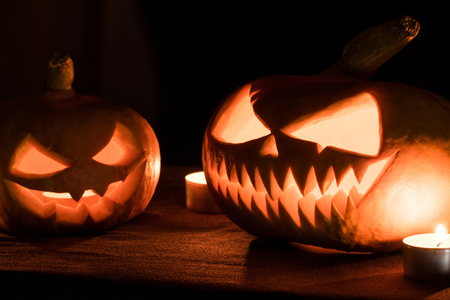 Two pumpkins are on the table, and candles are burning around. Halloween art design.の写真素材