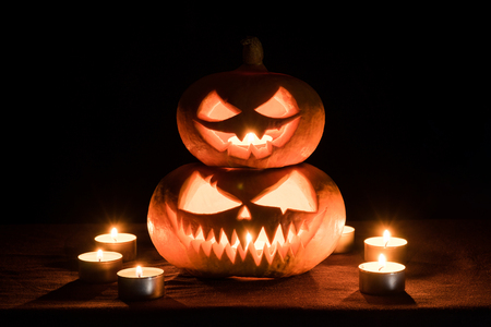 Two pumpkins are on the table, and candles are burning around. Halloween art design.の写真素材