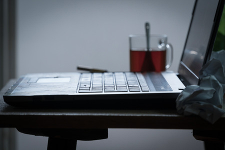 Workplace of a programmer or writer. The laptop is on the table with tea, beer and a cigarette.の写真素材