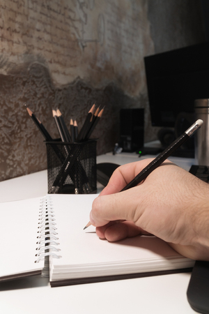 The guy writes with a pencil in a notebook. Man's hand with a pencilの写真素材