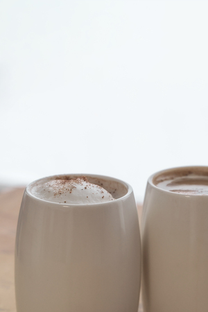 Two white cups of coffee stand on a world map against a light backgroundの写真素材