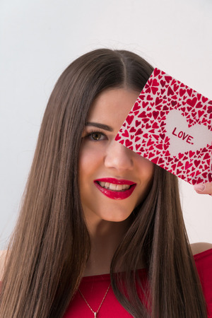 Portrait of a sweet perfect girl smiling at camera with heart shaped paper in her hands. Valentines Day or Womens Day conceptの写真素材